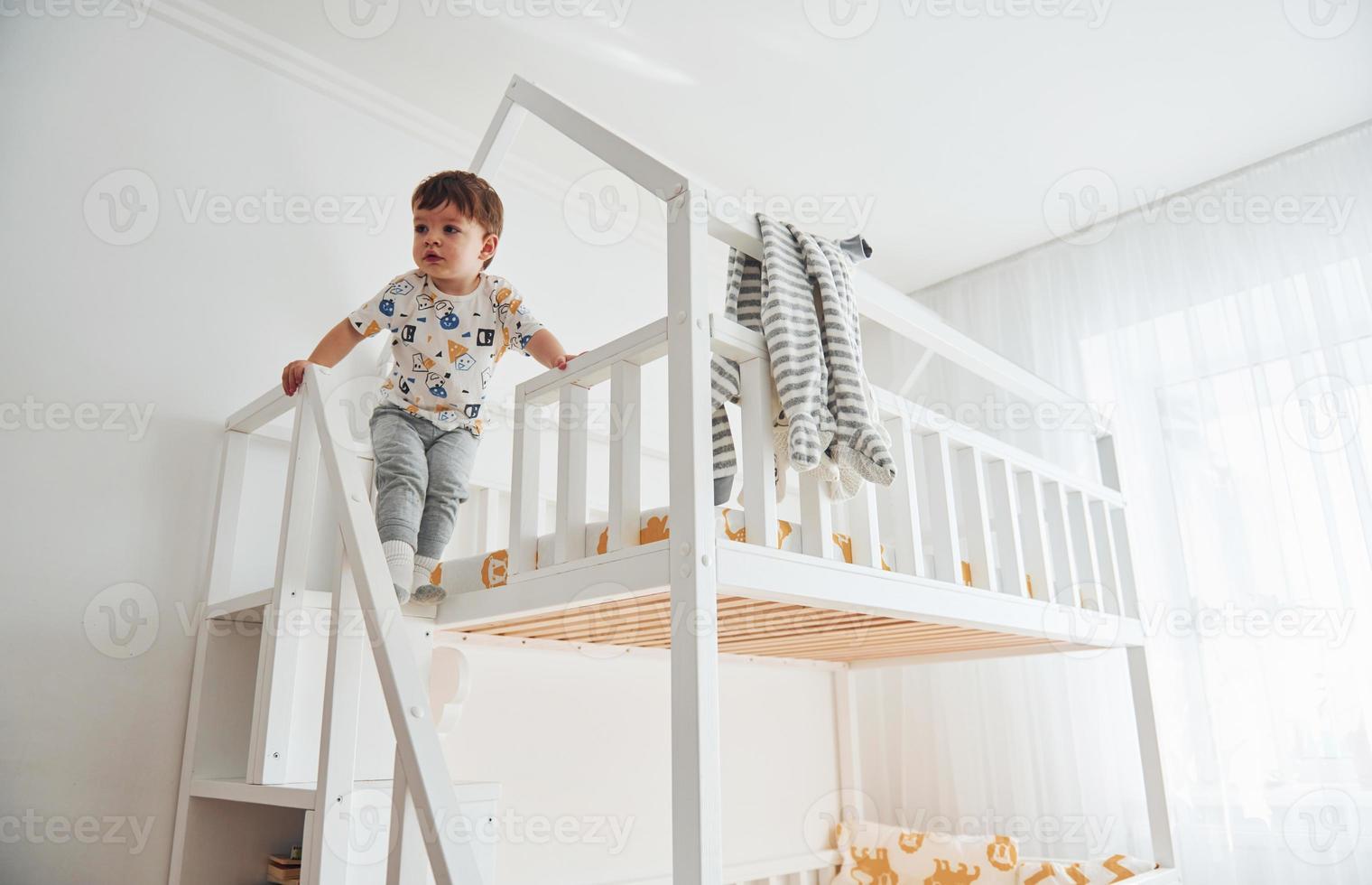 Cute little boy resting and have fun indoors in room on the bed photo