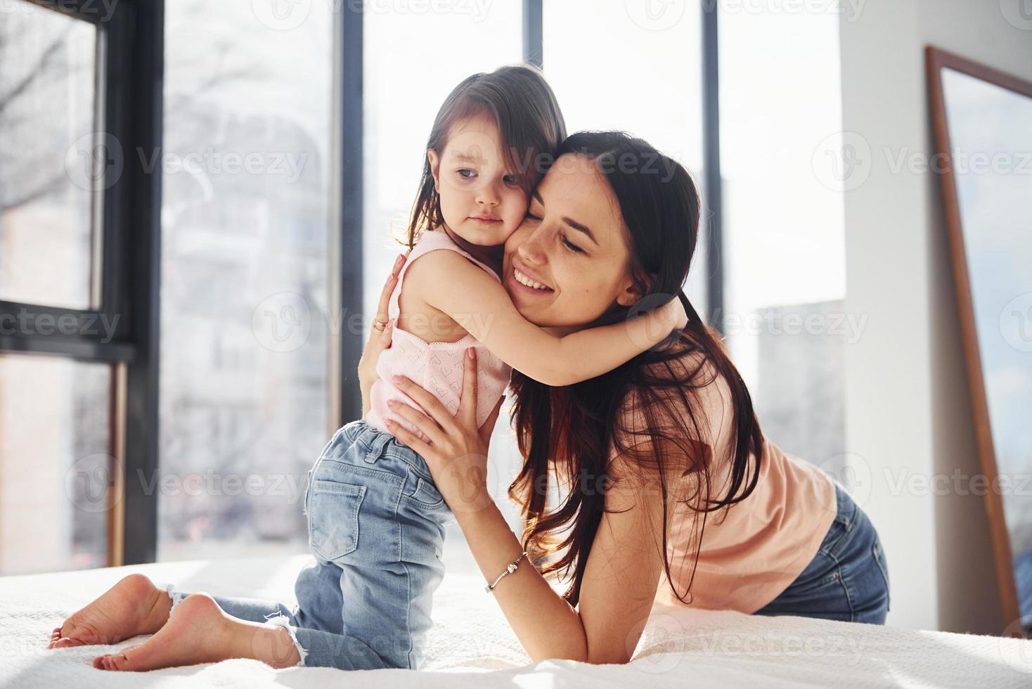 joven madre con su hija abrazándose en la cama foto