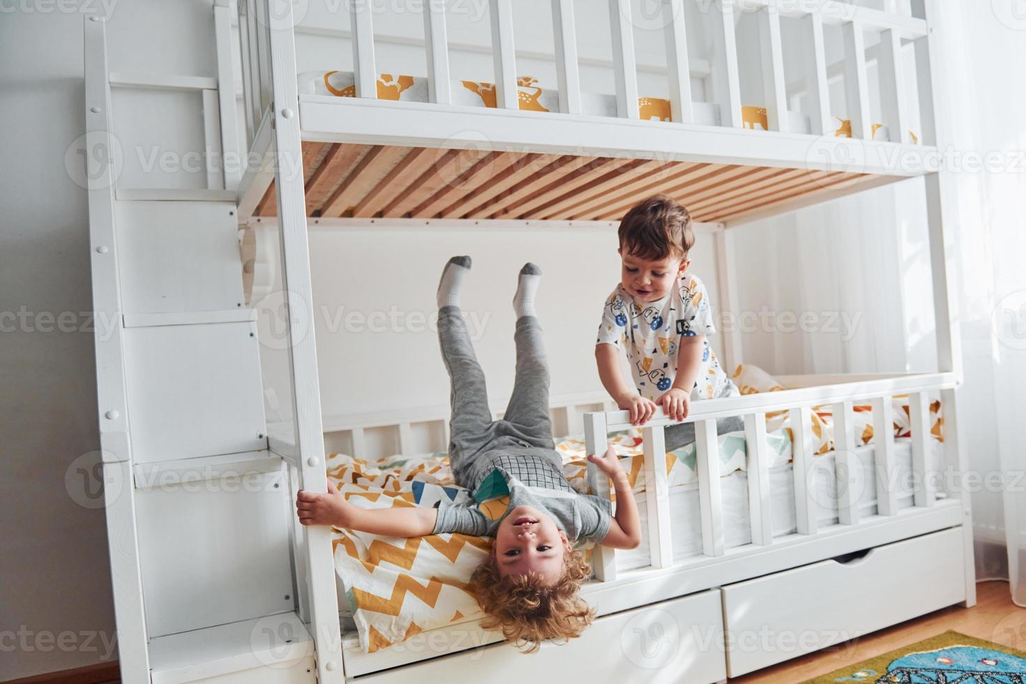 Two little boys resting and have fun indoors in the bedroom together photo