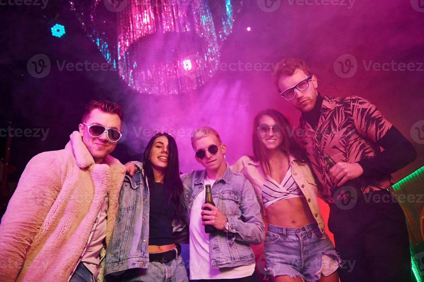 posando para la cámara. los jóvenes se divierten en el club nocturno con luces láser de colores foto