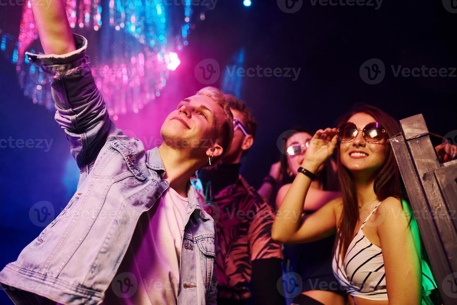 Young people making selfie in night club with colorful laser lights photo