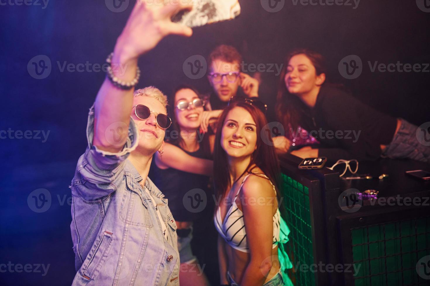 jóvenes haciendo selfie en club nocturno con luces láser de colores foto