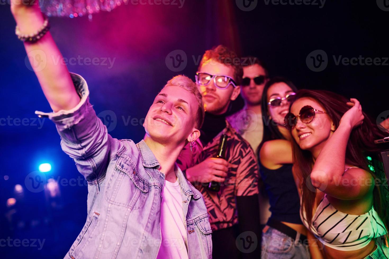 Young people making selfie in night club with colorful laser lights photo