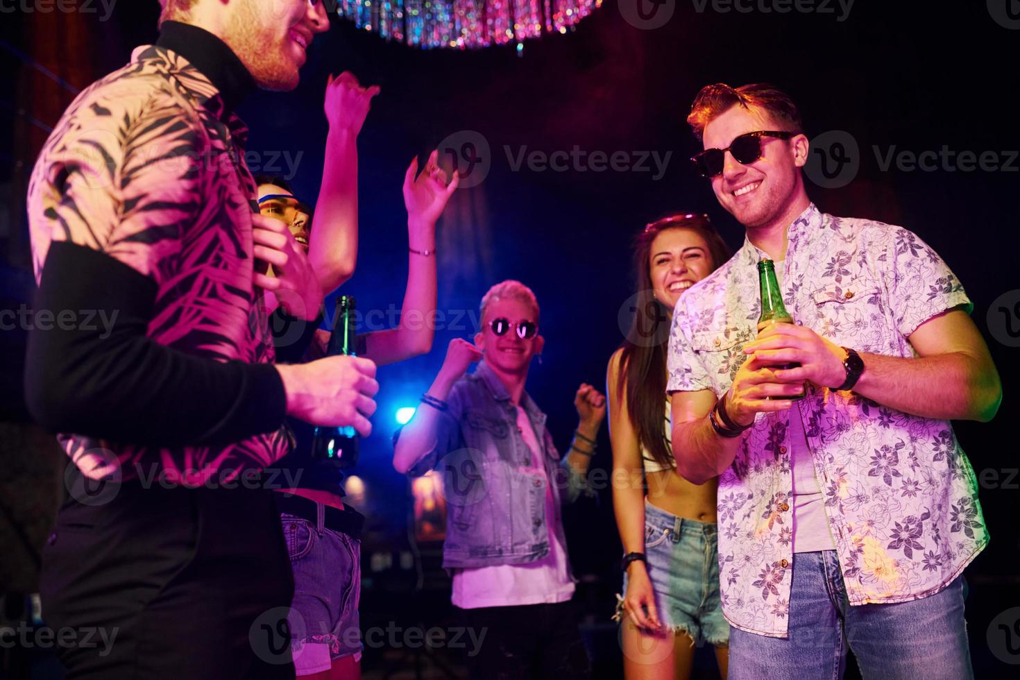Young people is having fun in night club with colorful laser lights photo