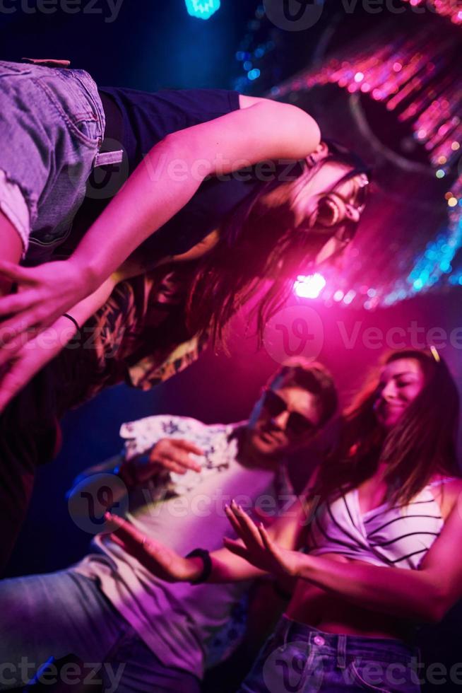 View from below of young people that having fun in night club with colorful laser lights photo