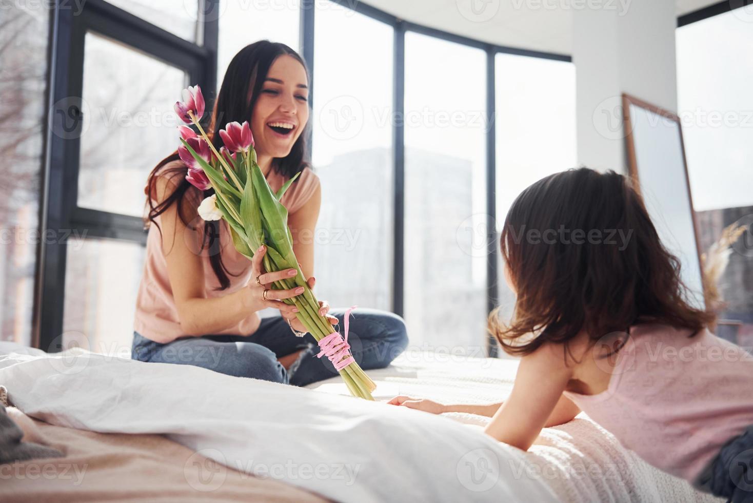 la hija felicita a la madre con las vacaciones y le da un ramo de flores foto