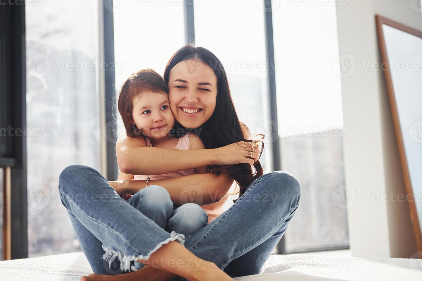 joven madre con su hija abrazándose en la cama foto