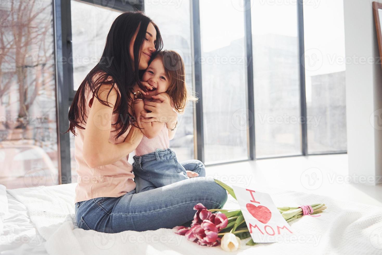 abrazándose unos a otros. la hija felicita a la madre con las vacaciones y le da un ramo de flores foto