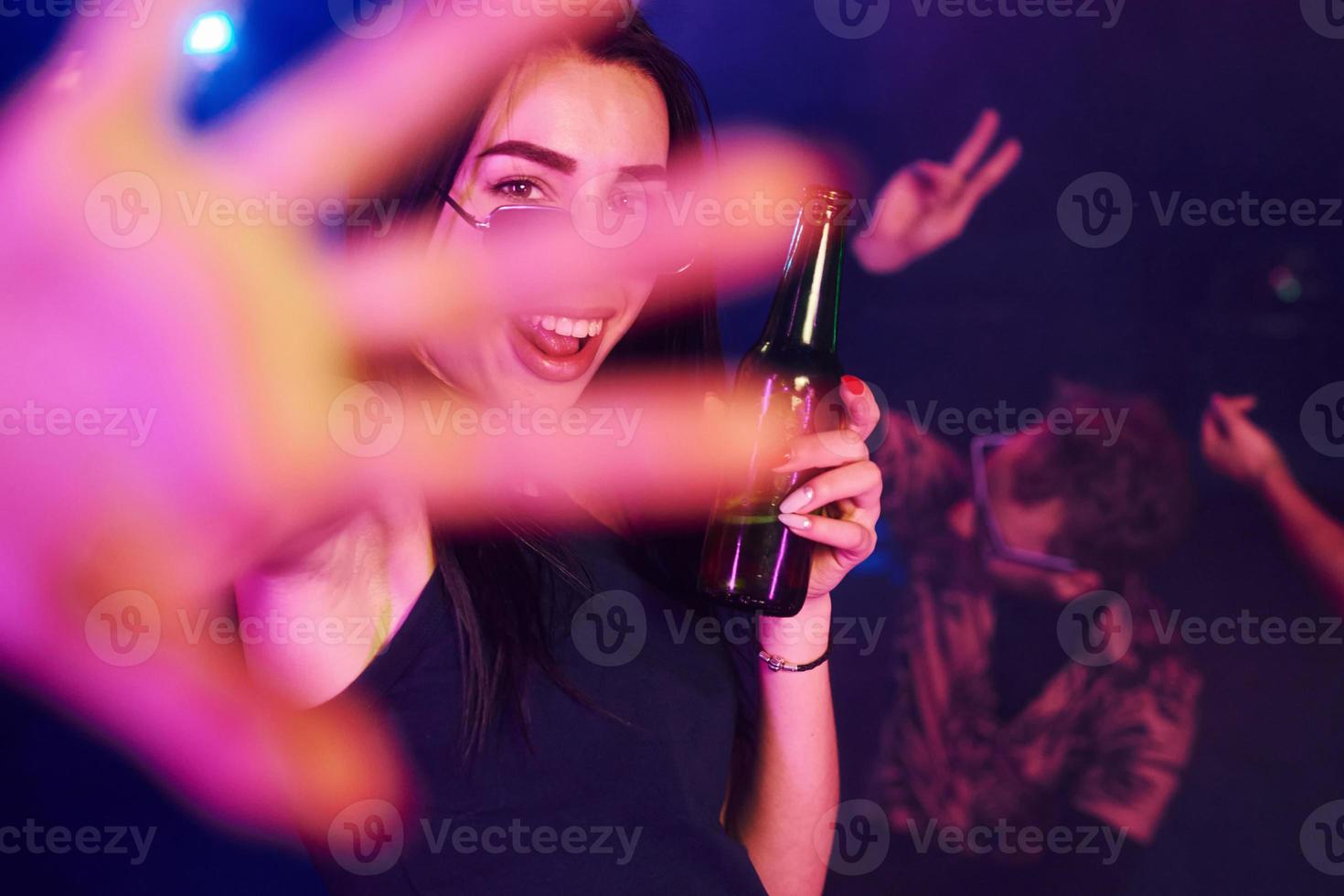 Defocused hand. Young people is having fun in night club with colorful laser lights photo