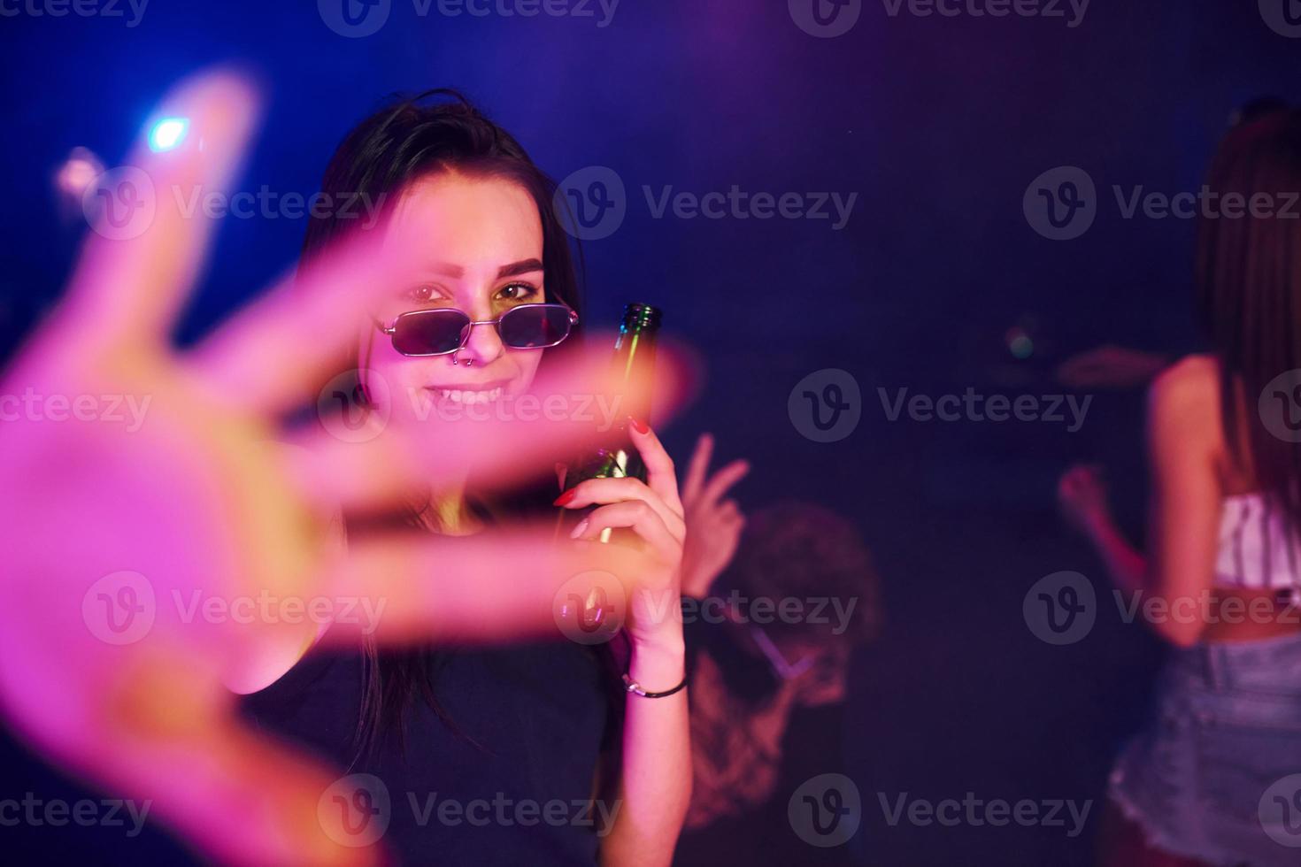 Defocused hand. Young people is having fun in night club with colorful laser lights photo