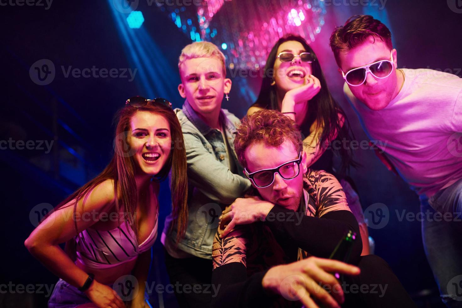 Going crazy and posing for the camera together. Young people is having fun in night club with colorful laser lights photo