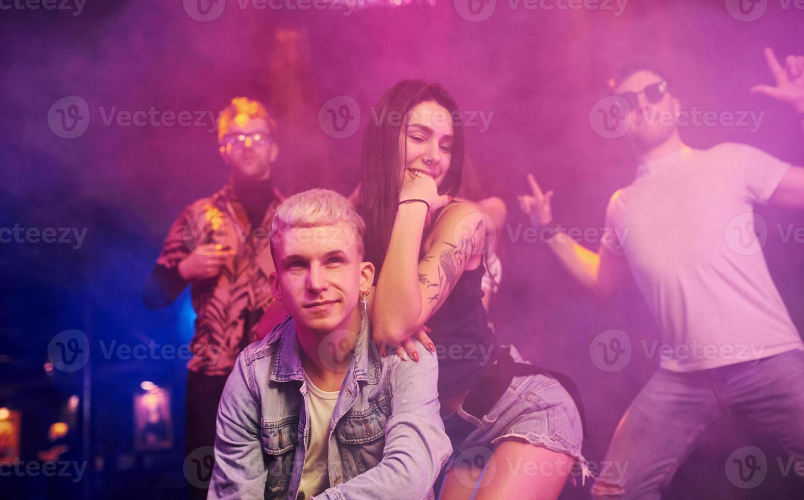 Going crazy and posing for the camera together. Young people is having fun in night club with colorful laser lights photo