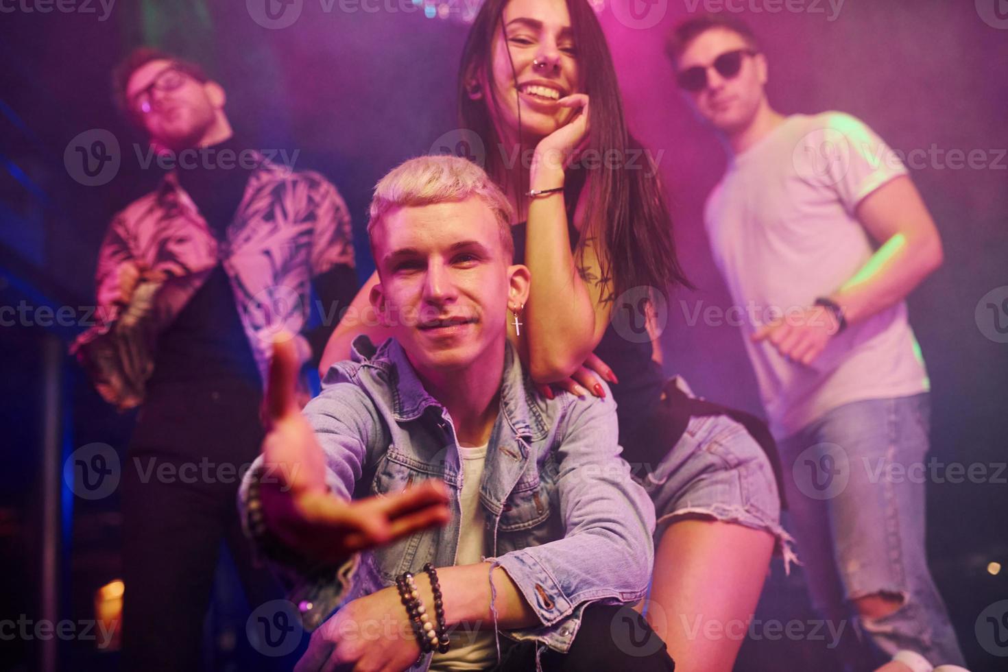 Going crazy and posing for the camera together. Young people is having fun in night club with colorful laser lights photo