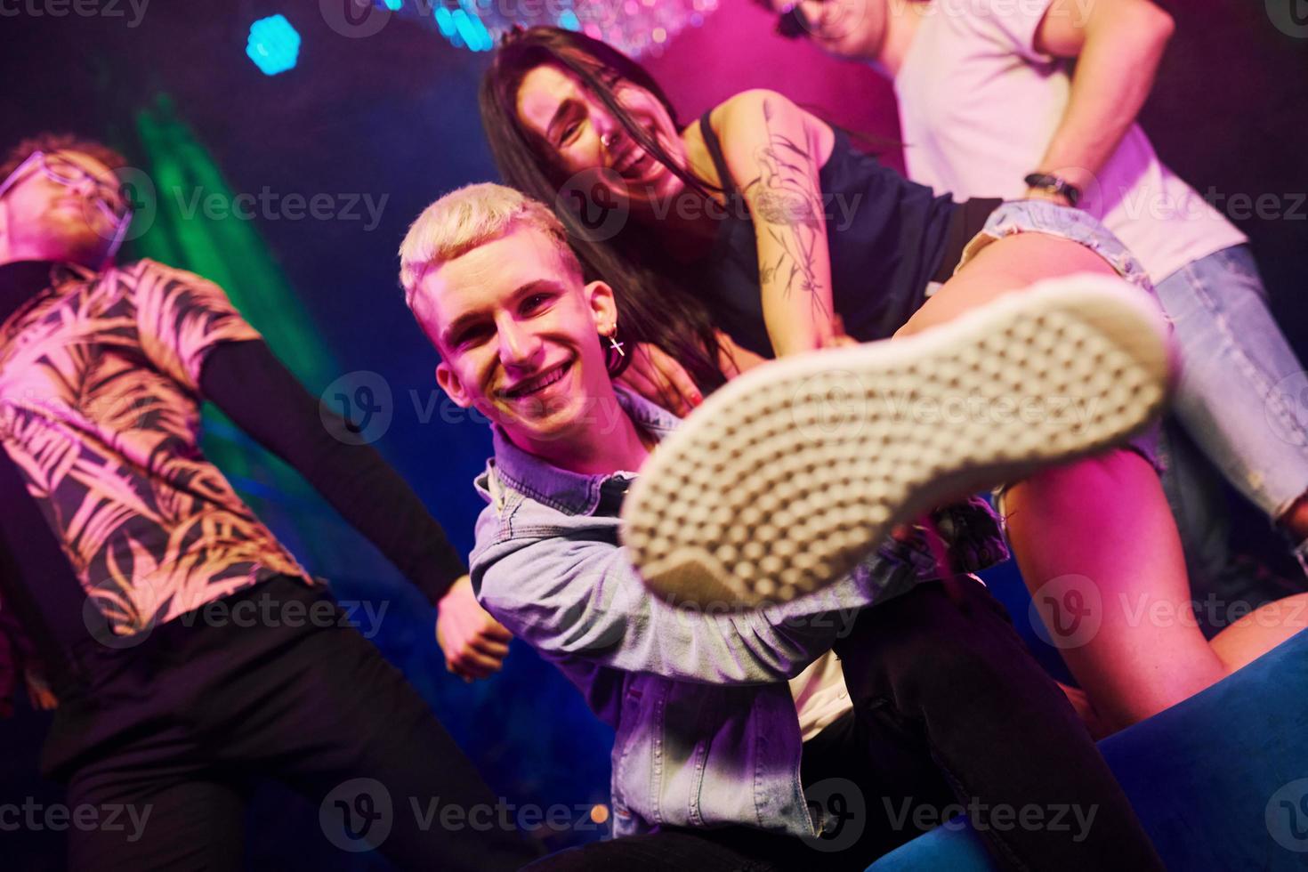 Going crazy and posing for the camera together. Young people is having fun in night club with colorful laser lights photo