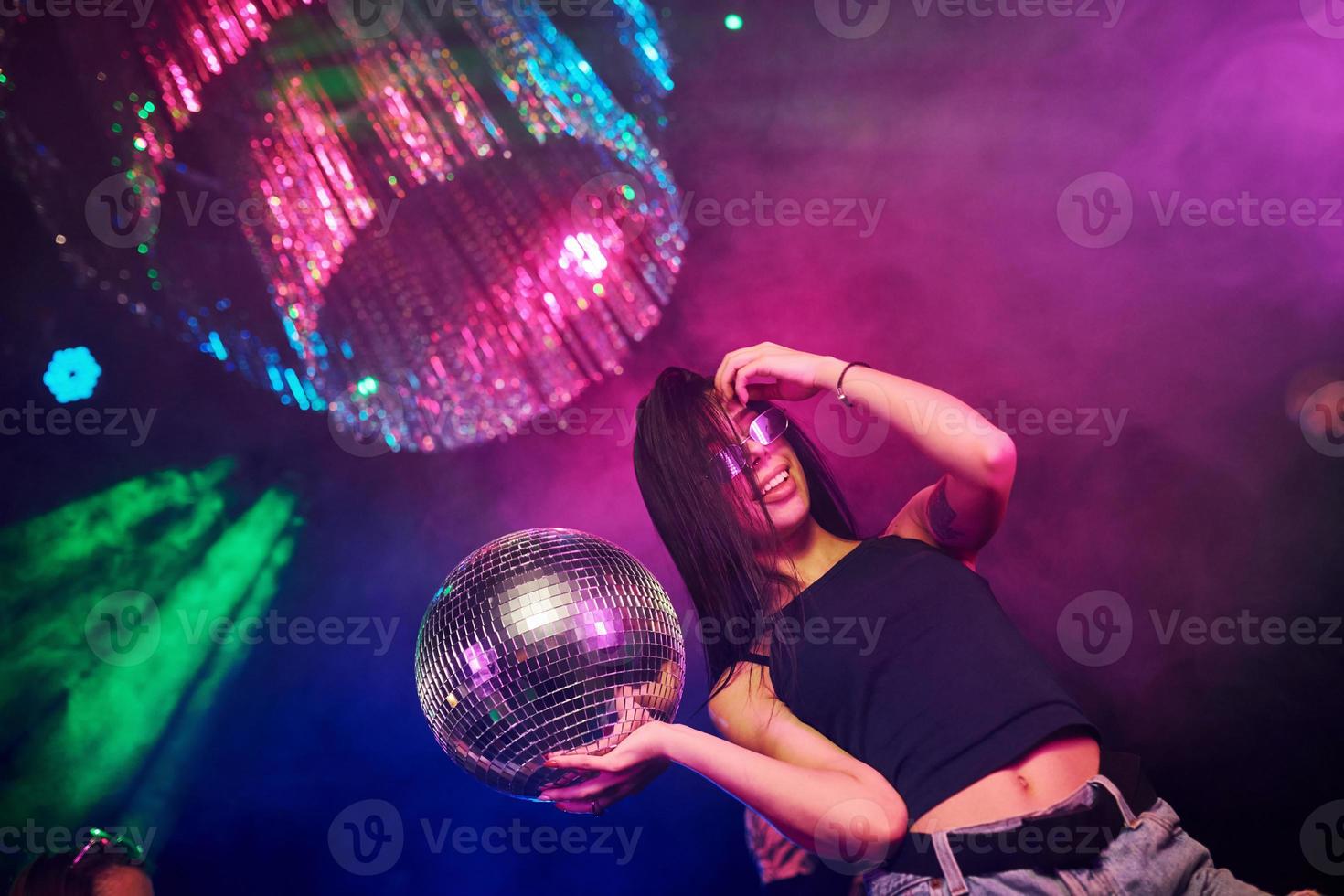 hermosa joven diviértete, bailando en el club nocturno. sosteniendo la pelota de fiesta foto