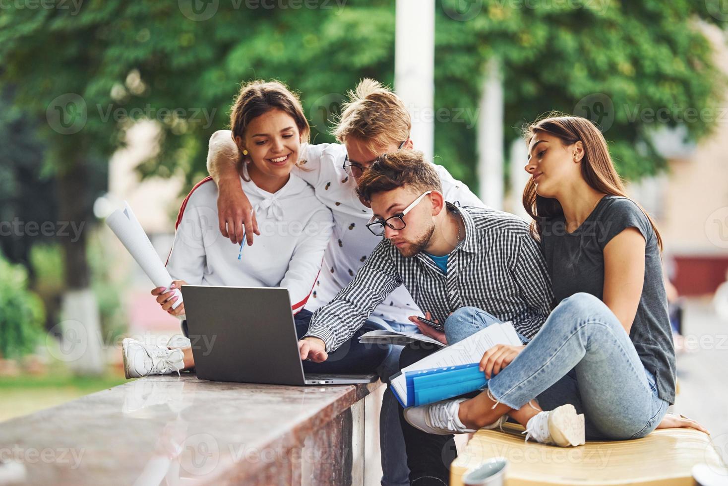 concentrado en el trabajo. con computadora portátil grupo de jóvenes estudiantes con ropa informal en la ciudad durante el día foto