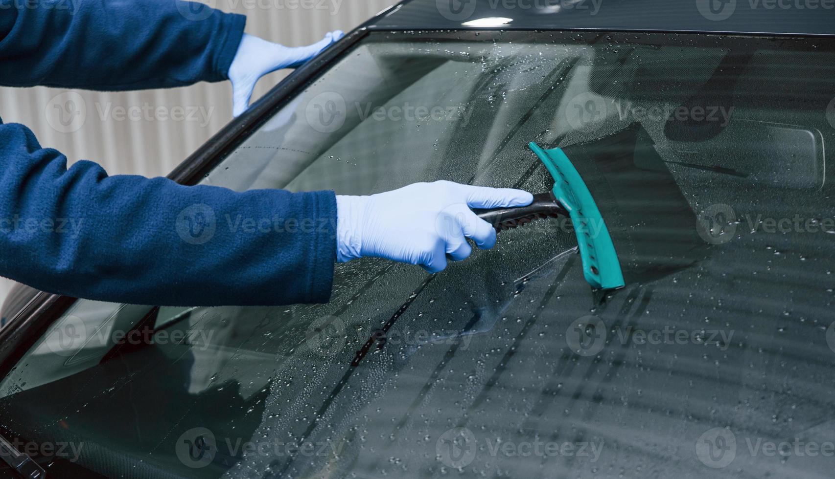 Male worker in uniform washing new modern car. Conception of service photo