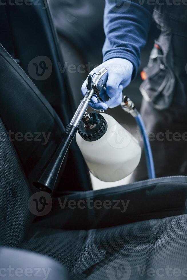 Male worker in uniform cleaning new modern car. Conception of service photo