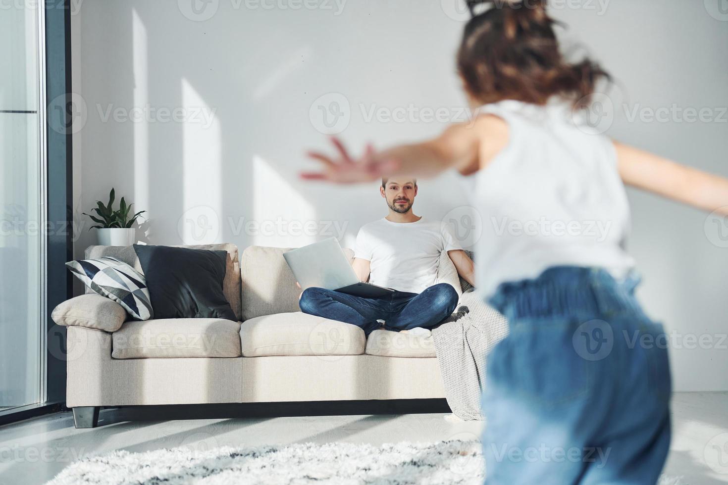 Happy father with his daughter spending free time with laptop at home together photo