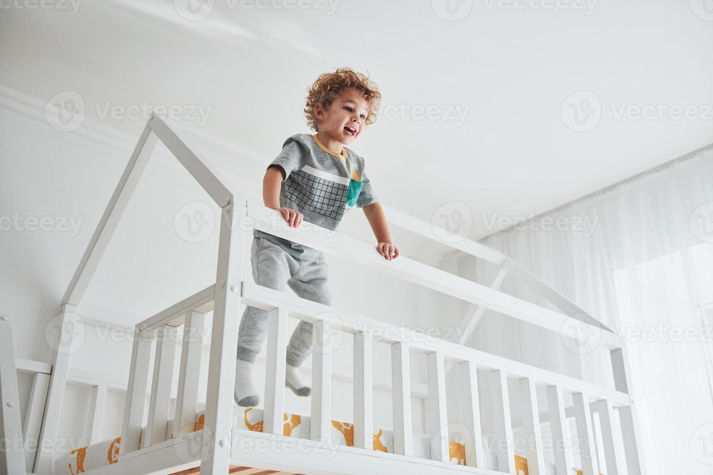 lindo niño descansando y divirtiéndose en el interior de la habitación en la cama foto