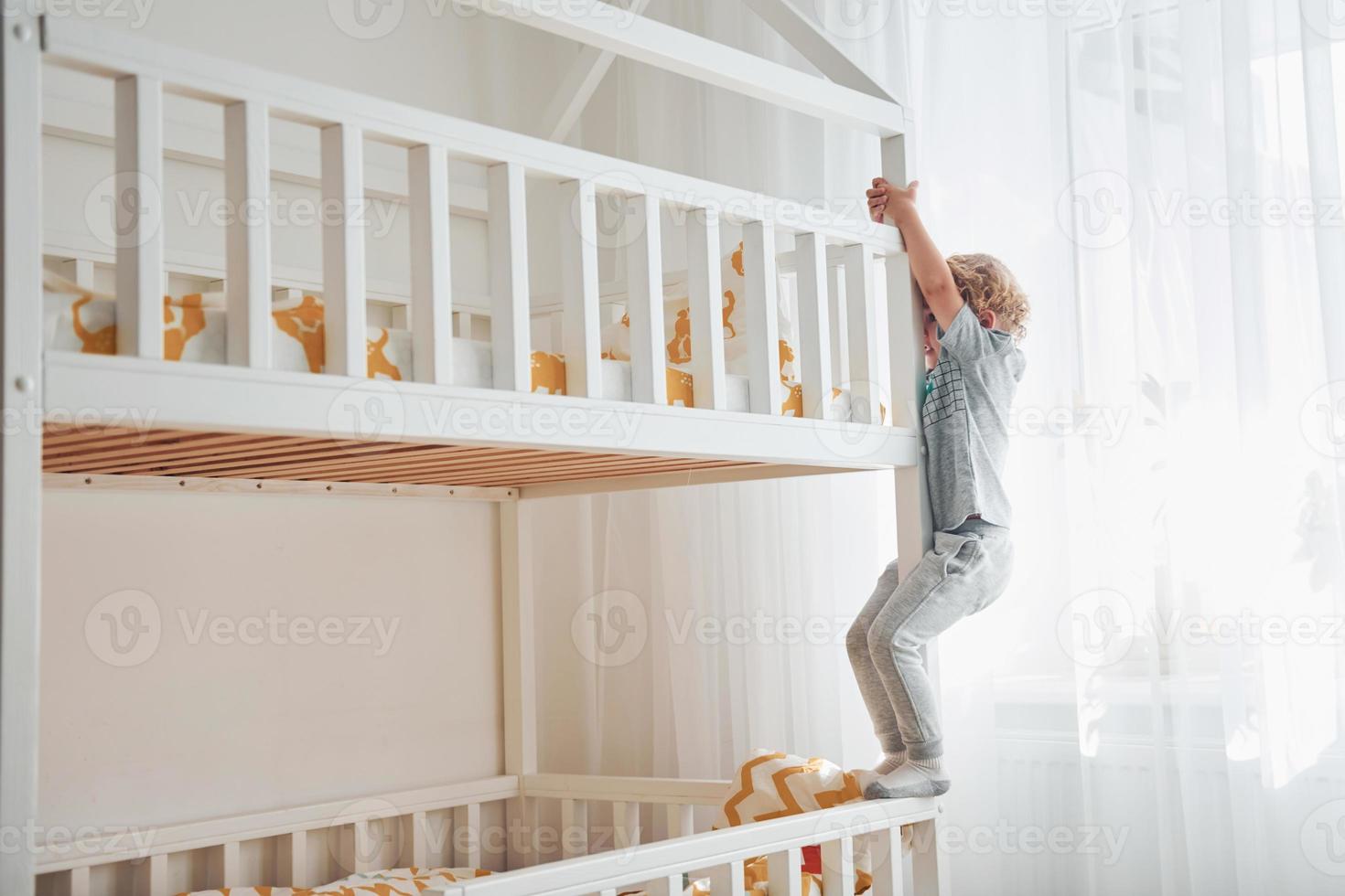 lindo niño descansando y divirtiéndose en el interior de la habitación en la cama foto