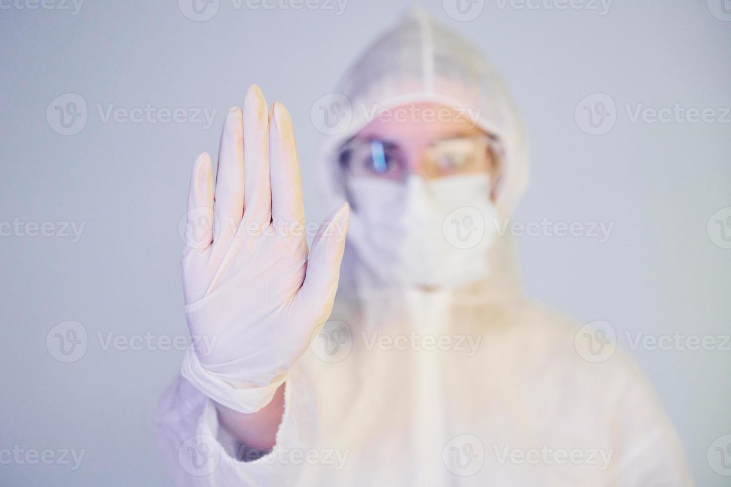 Stop the virus sign. Portrait of female doctor scientist in lab coat, defensive eyewear and mask photo