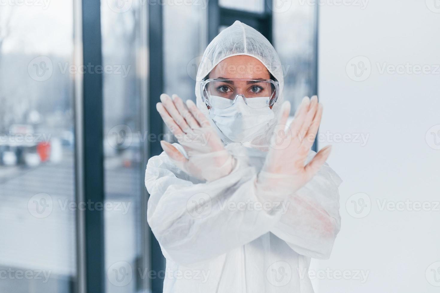 detener el signo del virus. retrato de una doctora científica con bata de laboratorio, anteojos defensivos y máscara foto