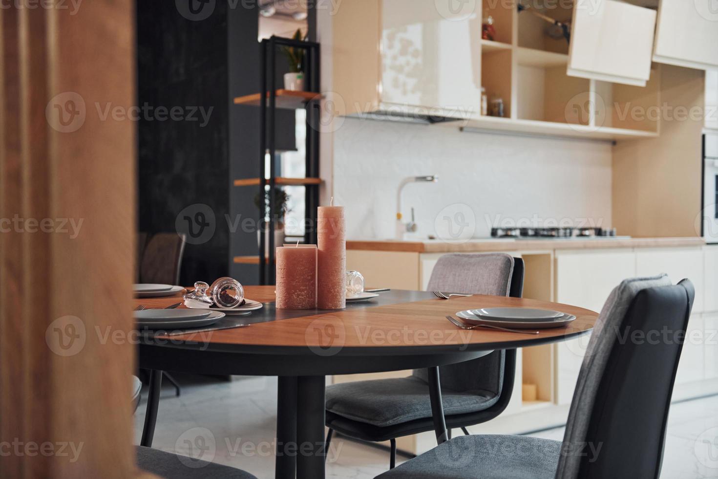 Interior of modern new kitchen with table and candles with plates on it photo