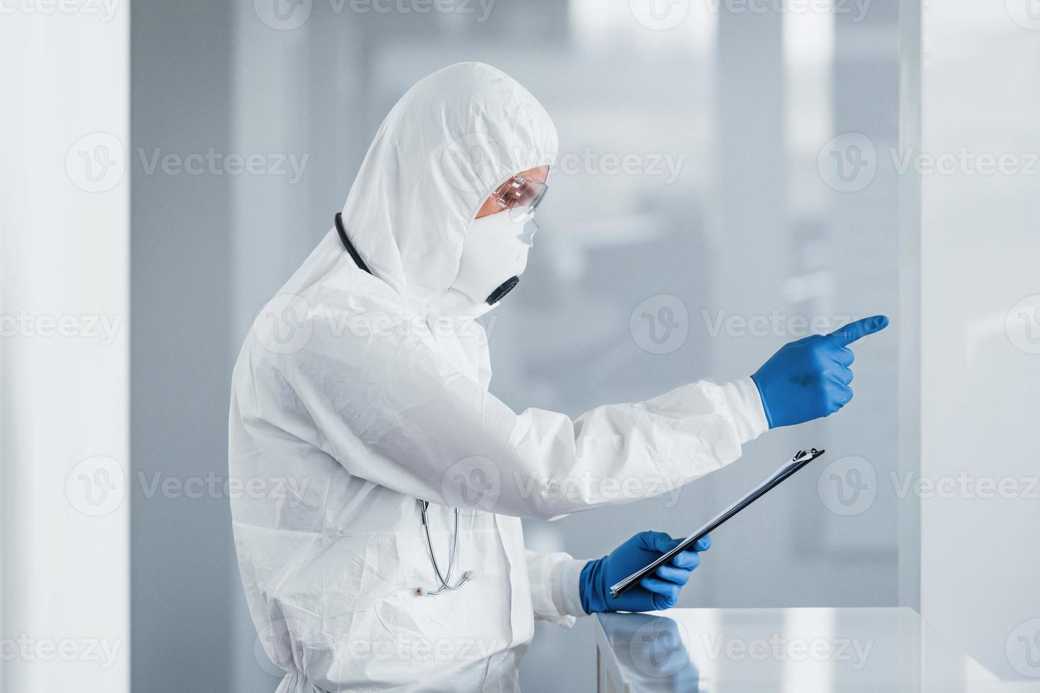 médico científico masculino en bata de laboratorio, anteojos defensivos y máscara foto