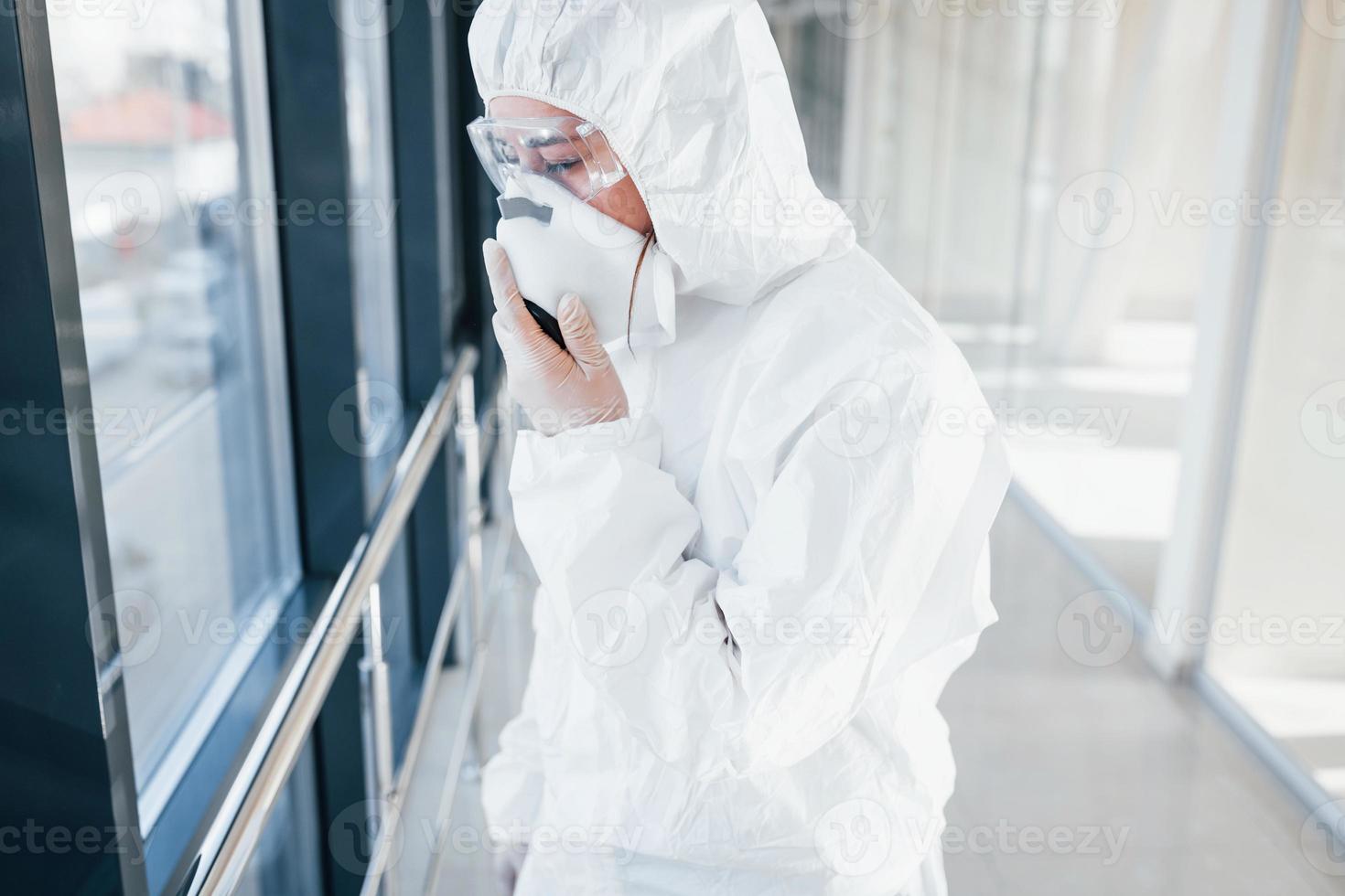 Female doctor scientist in lab coat, defensive eyewear and mask standing indoors photo