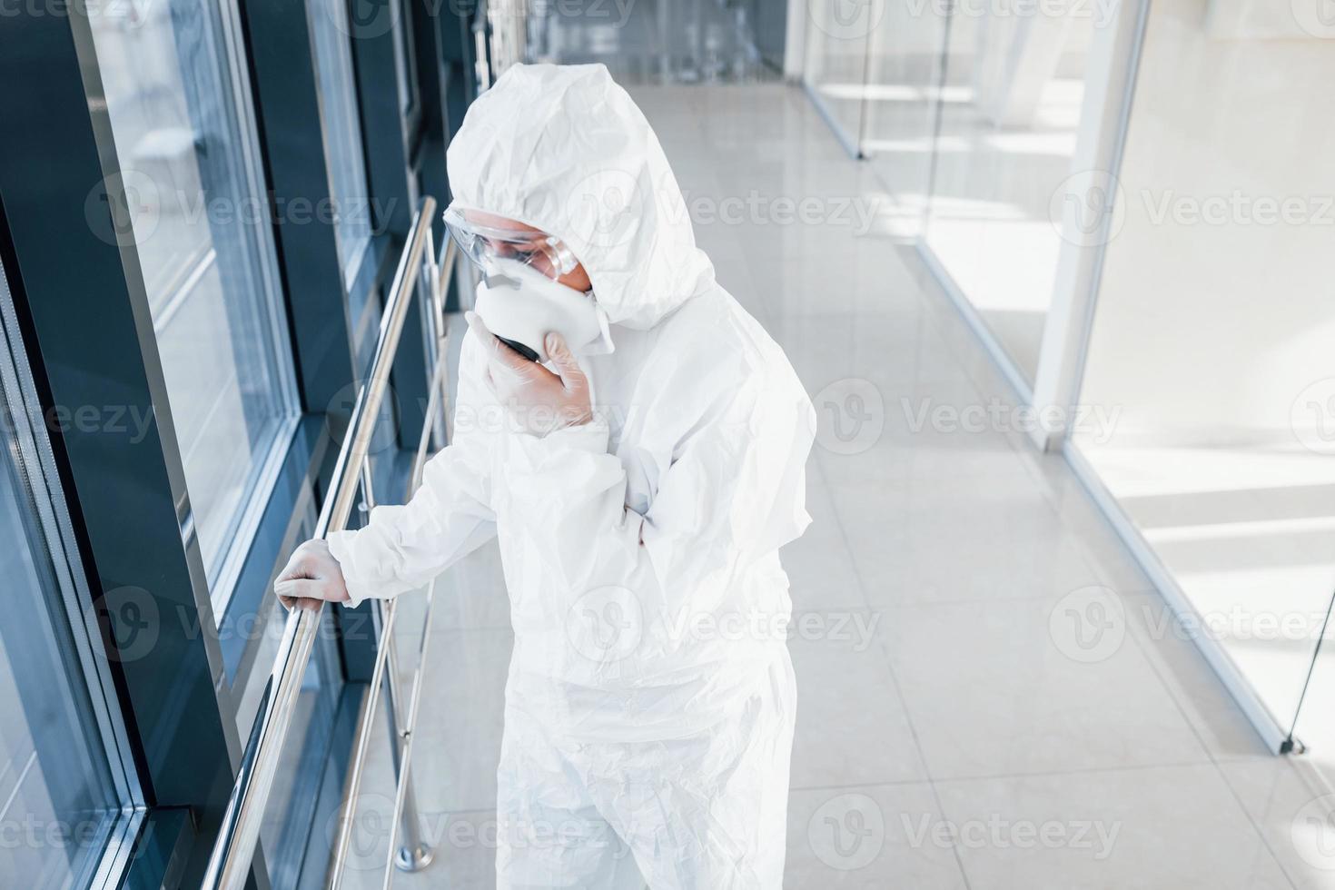 Female doctor scientist in lab coat, defensive eyewear and mask standing indoors photo