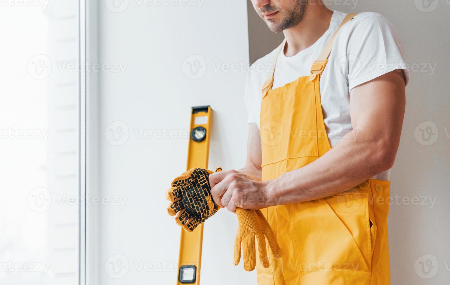 Handyman in yellow uniform preparing for work indoors. House renovation conception photo