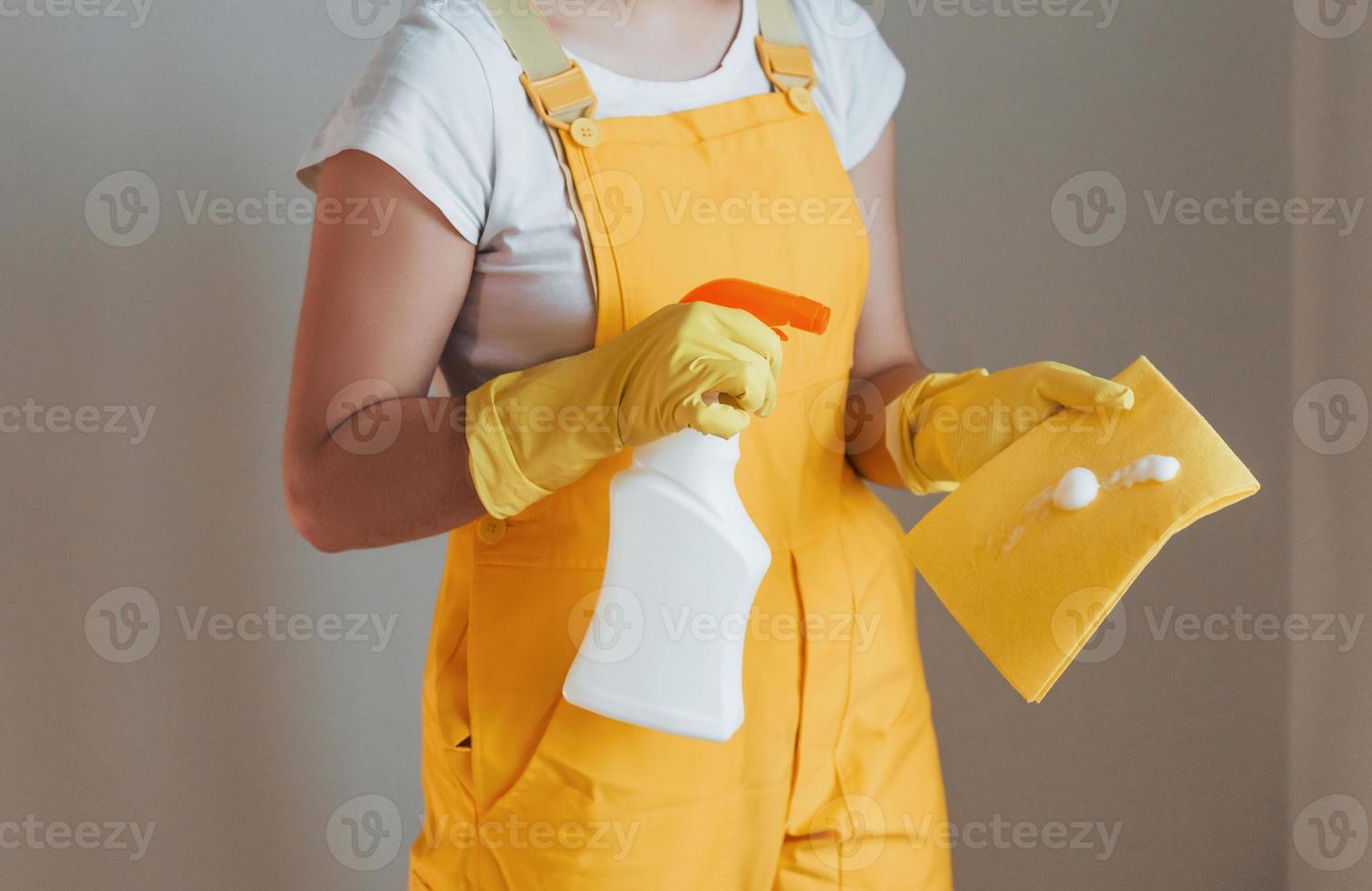 Housewife in yellow uniform preparing for polishing windows indoors. House renovation conception photo