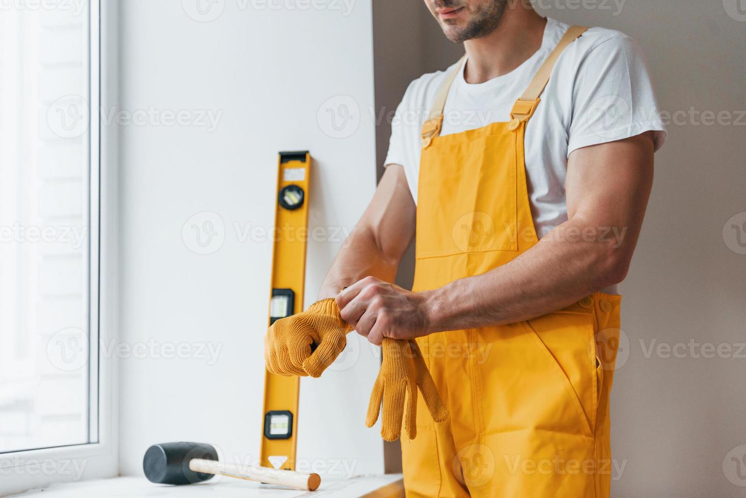 Handyman in yellow uniform preparing for work indoors. House renovation conception photo