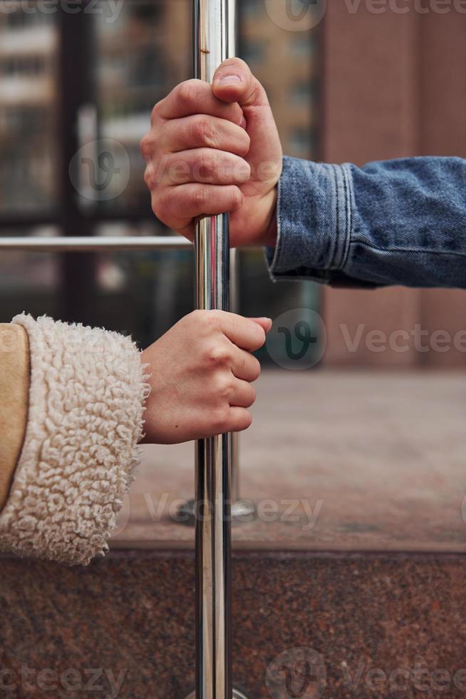 Close up view of woman's and man's hands that holding silver colored railing at quarantine time photo