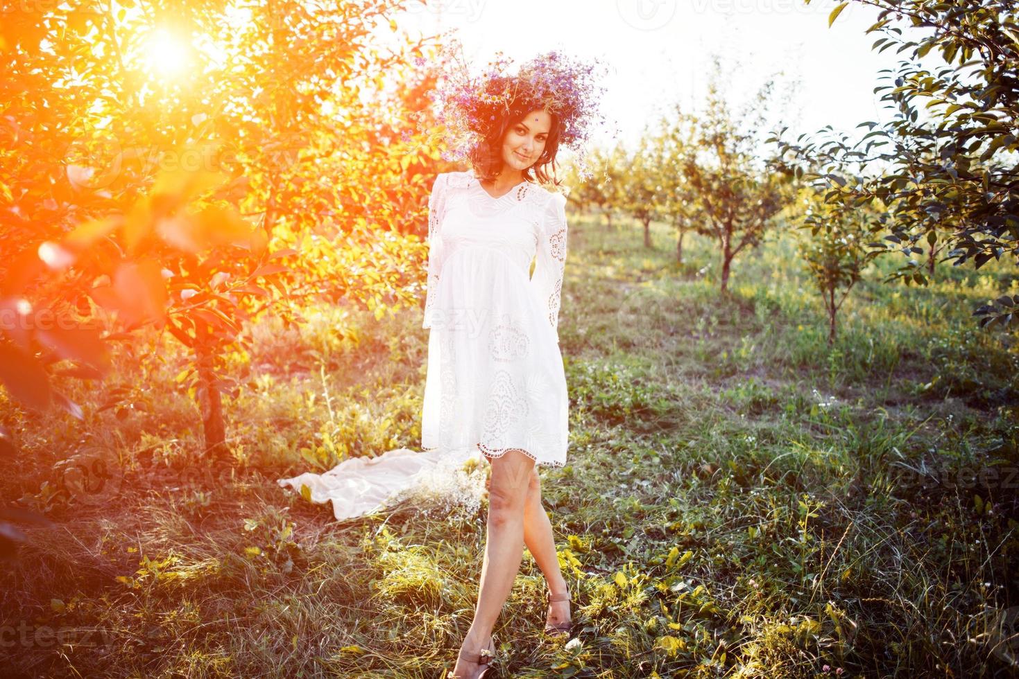 beautiful young woman with flower wreath in the garden photo