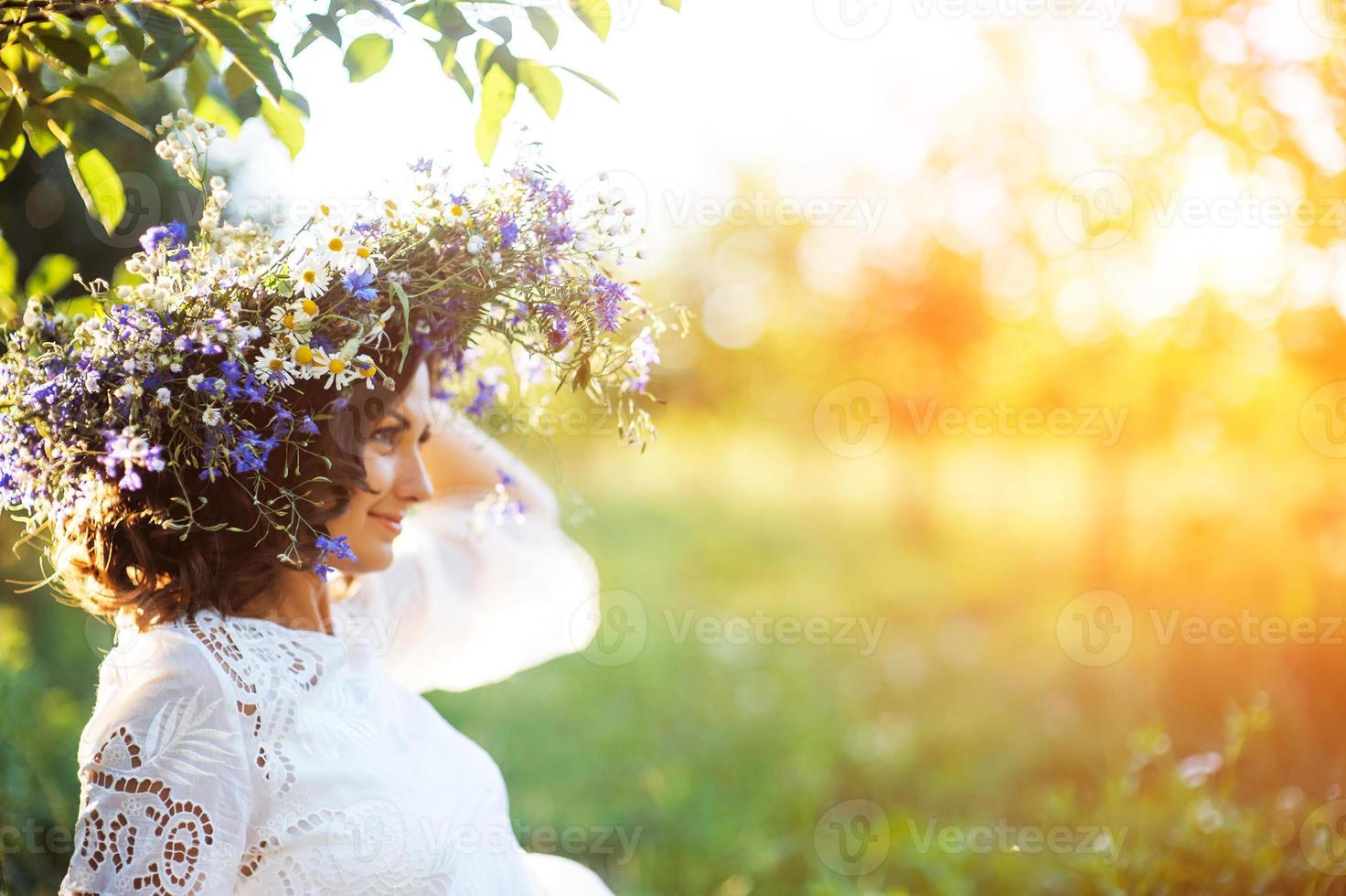 hermosa mujer joven con corona de flores en el jardín foto