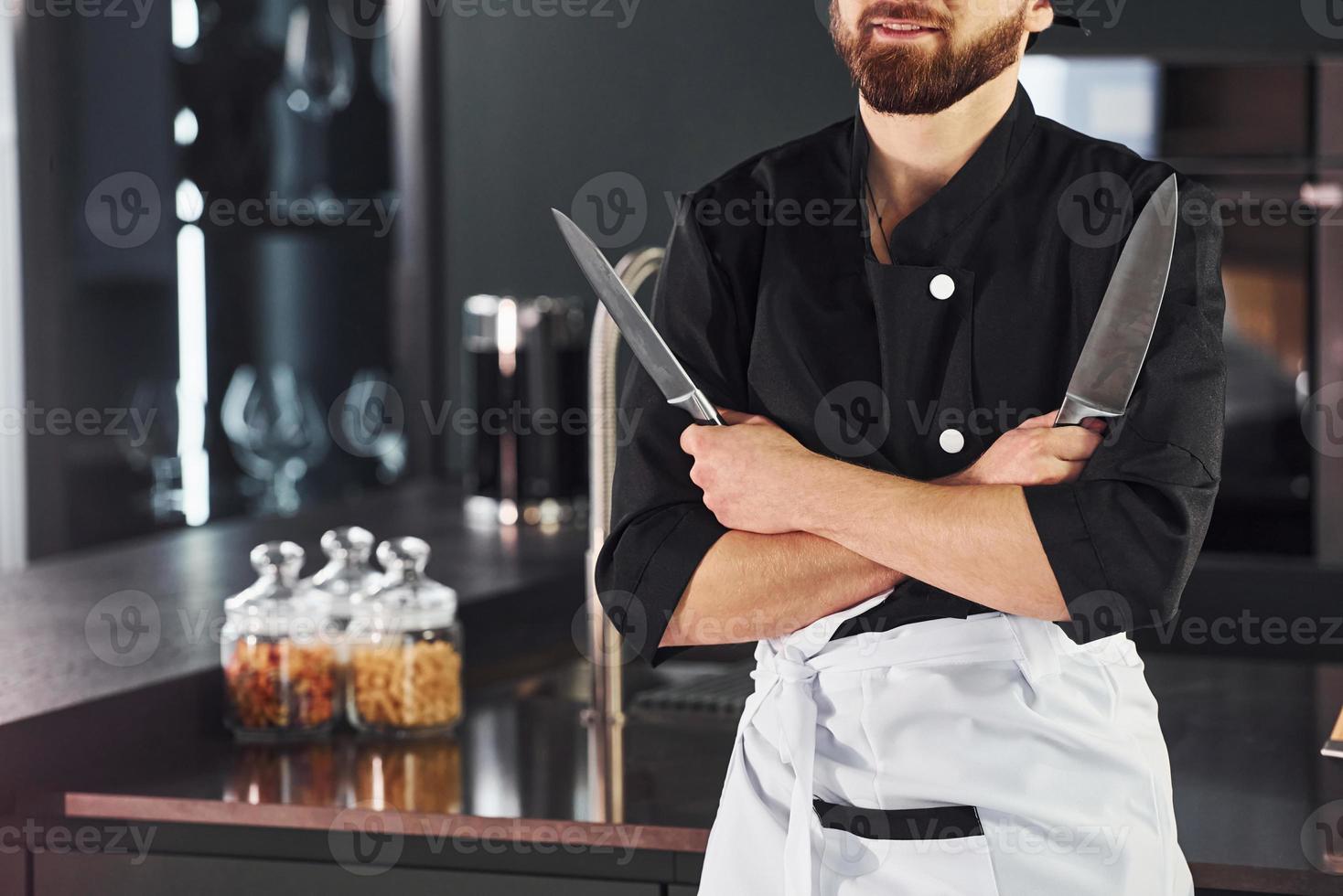 Professional young chef cook in uniform standing and preparing for the work on kitchen photo