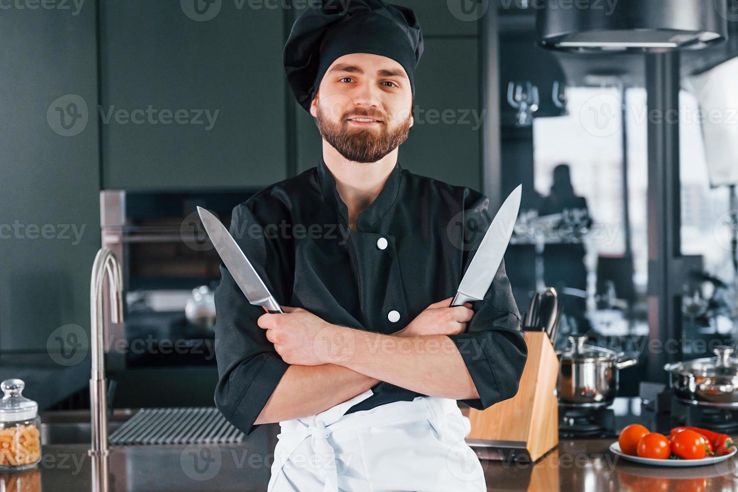 Portrait of professional young chef cook in uniform that posing for camera on the kitchen photo