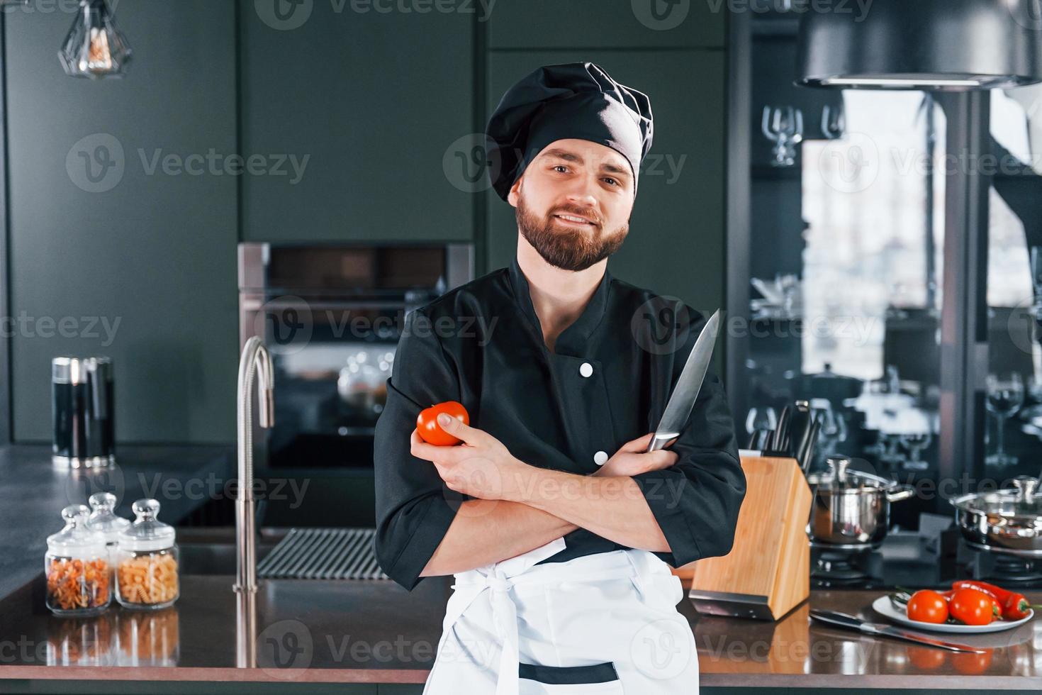 Portrait of professional young chef cook in uniform that posing for camera on the kitchen photo