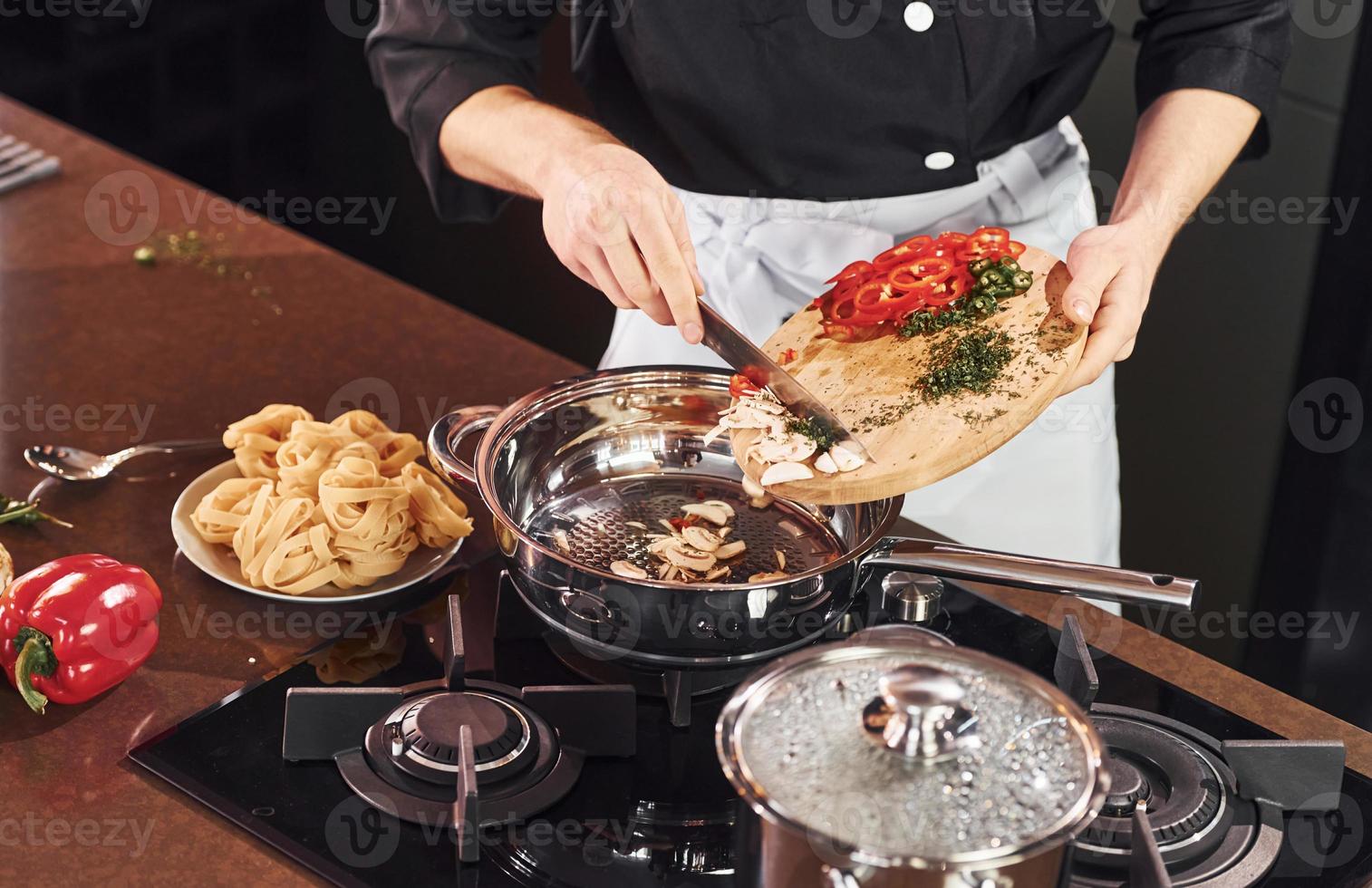 Using equipment. Professional young chef cook in uniform working on the kitchen with vegetables photo