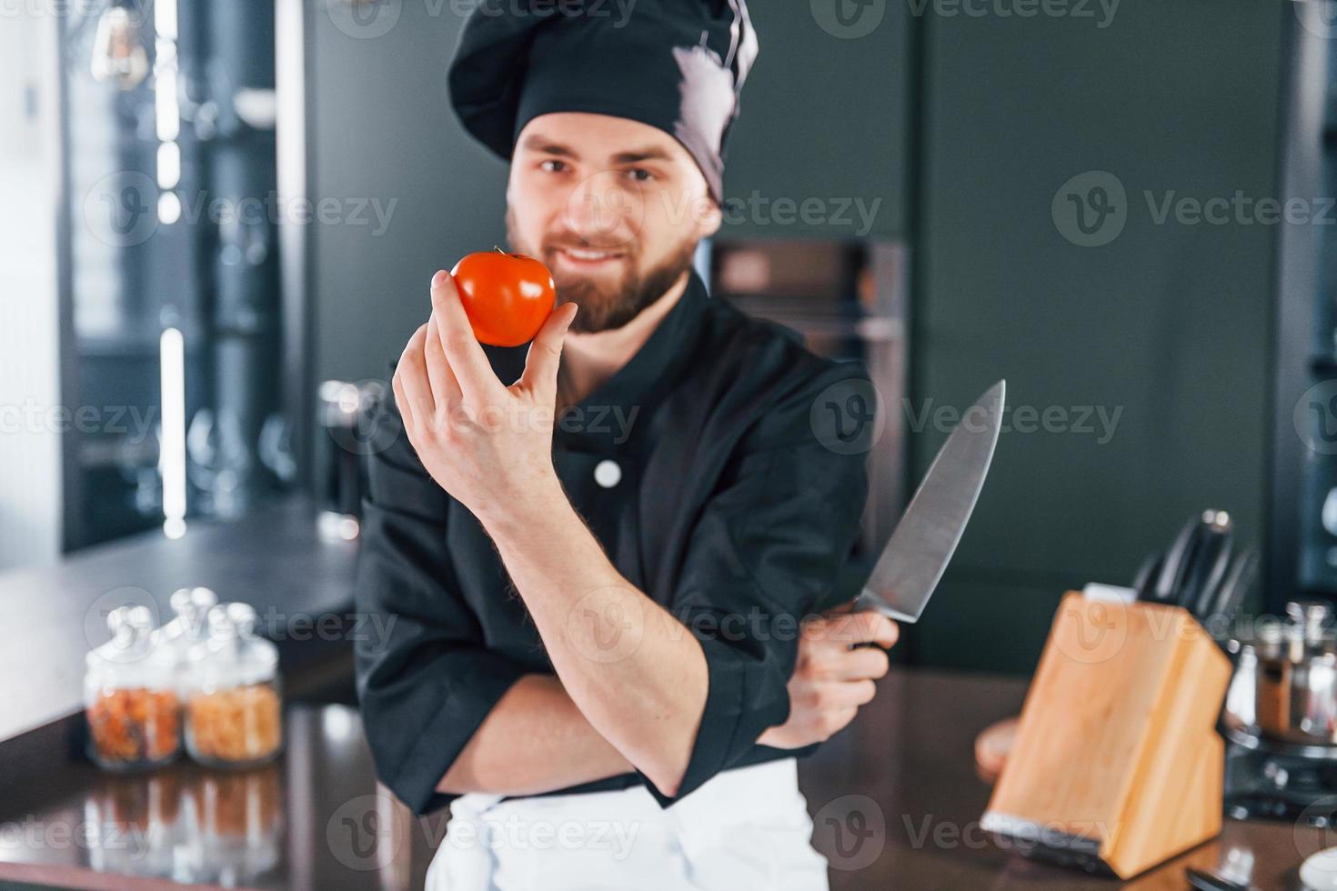 Portrait of professional young chef cook in uniform that posing for camera on the kitchen photo