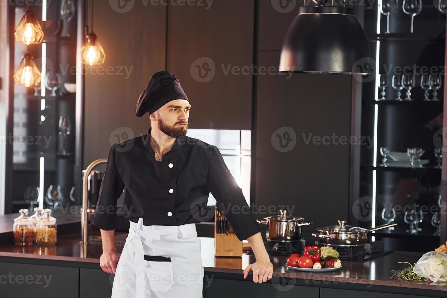 Portrait of professional young chef cook in uniform that posing for camera on the kitchen photo