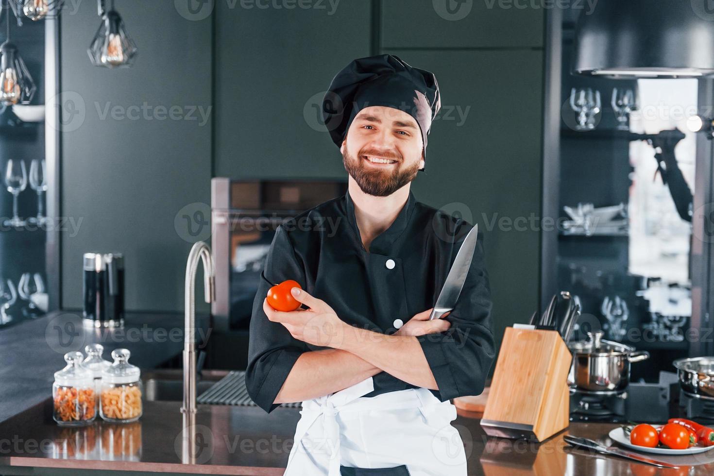 Portrait of professional young chef cook in uniform that posing for camera on the kitchen photo