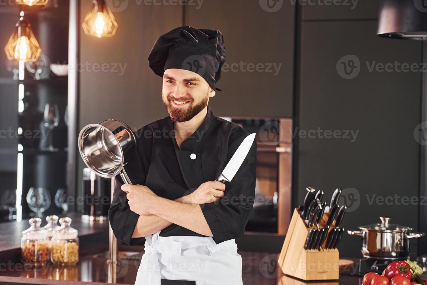 Portrait of professional young chef cook in uniform that posing for camera on the kitchen photo