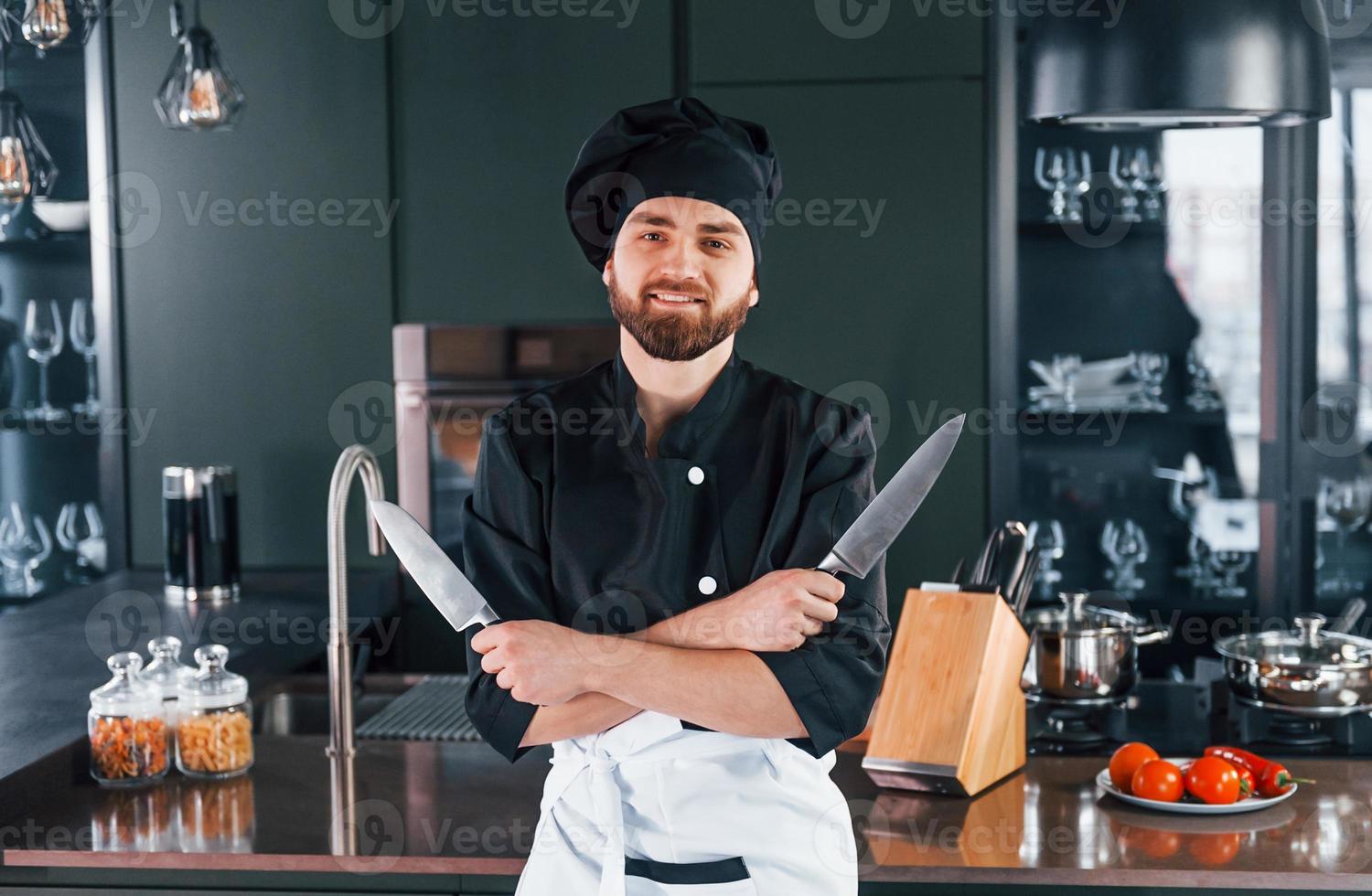 Portrait of professional young chef cook in uniform that posing for camera on the kitchen photo