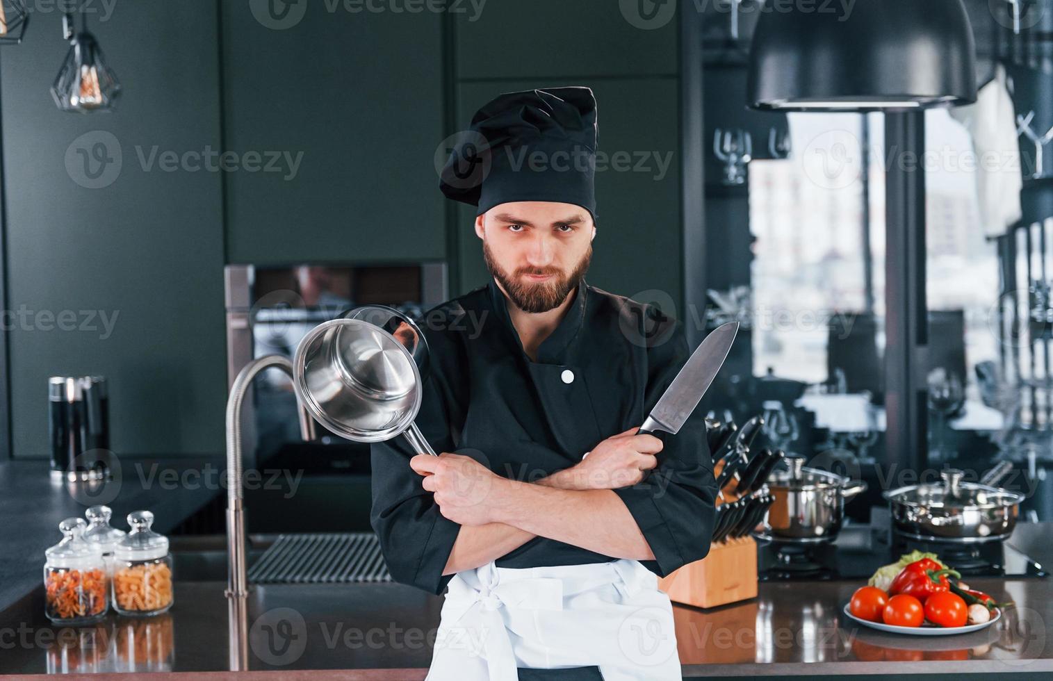 Portrait of professional young chef cook in uniform that posing for camera on the kitchen photo