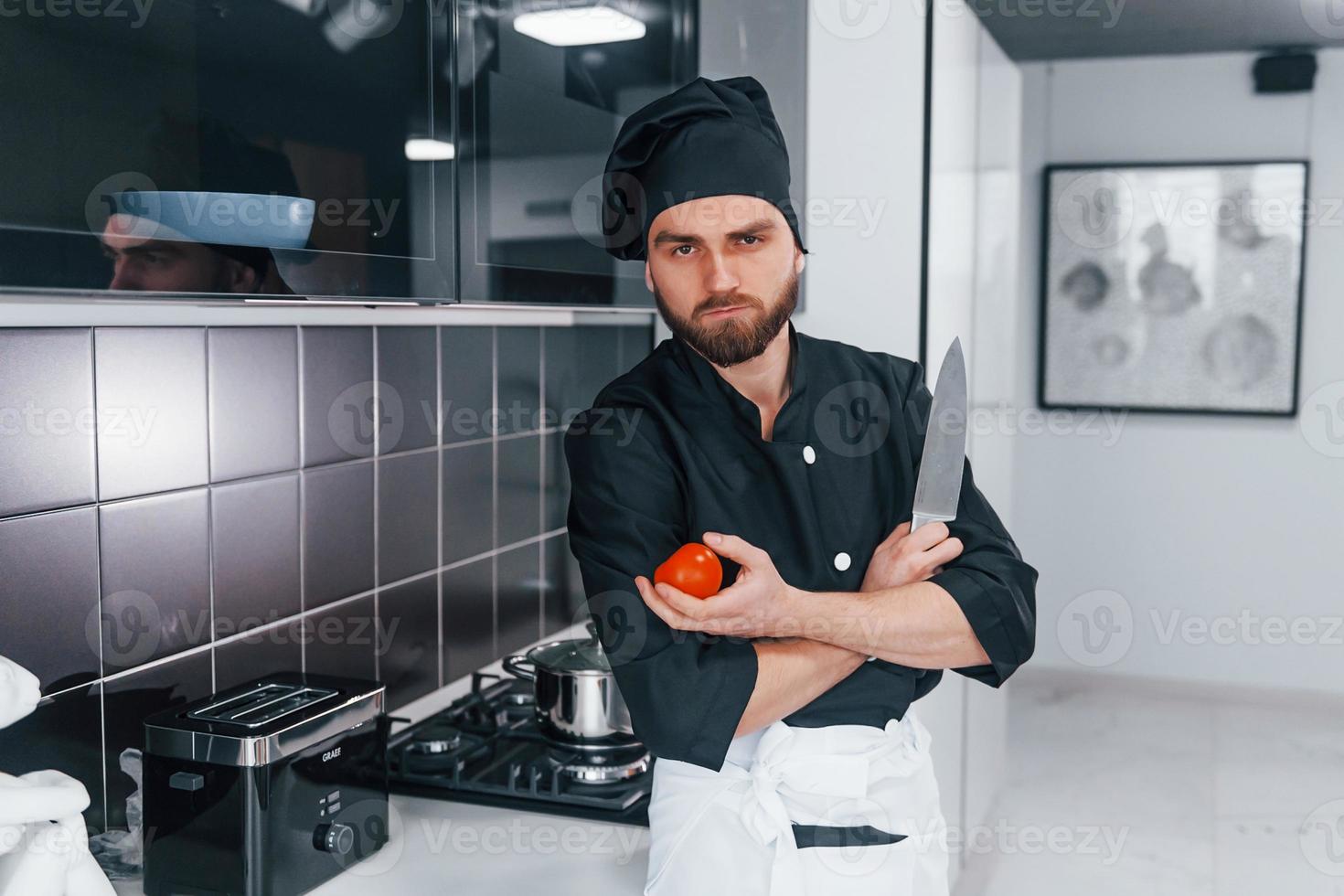 Professional young chef cook in uniform standing on the kitchen photo