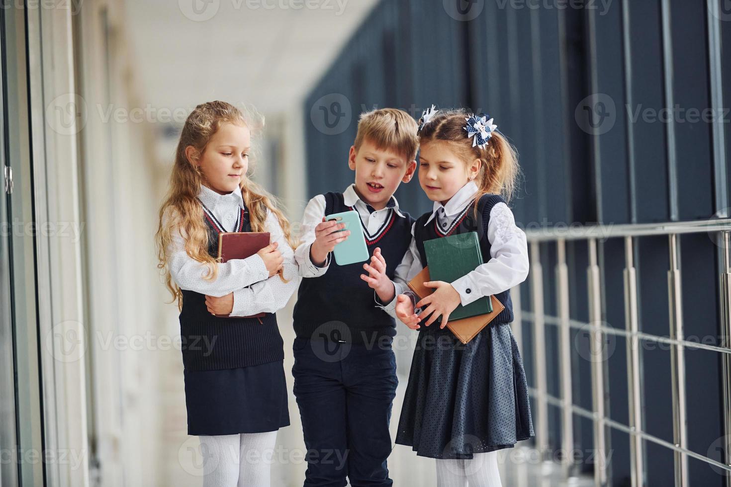 School kids in uniform together with phone in corridor. Conception of education photo