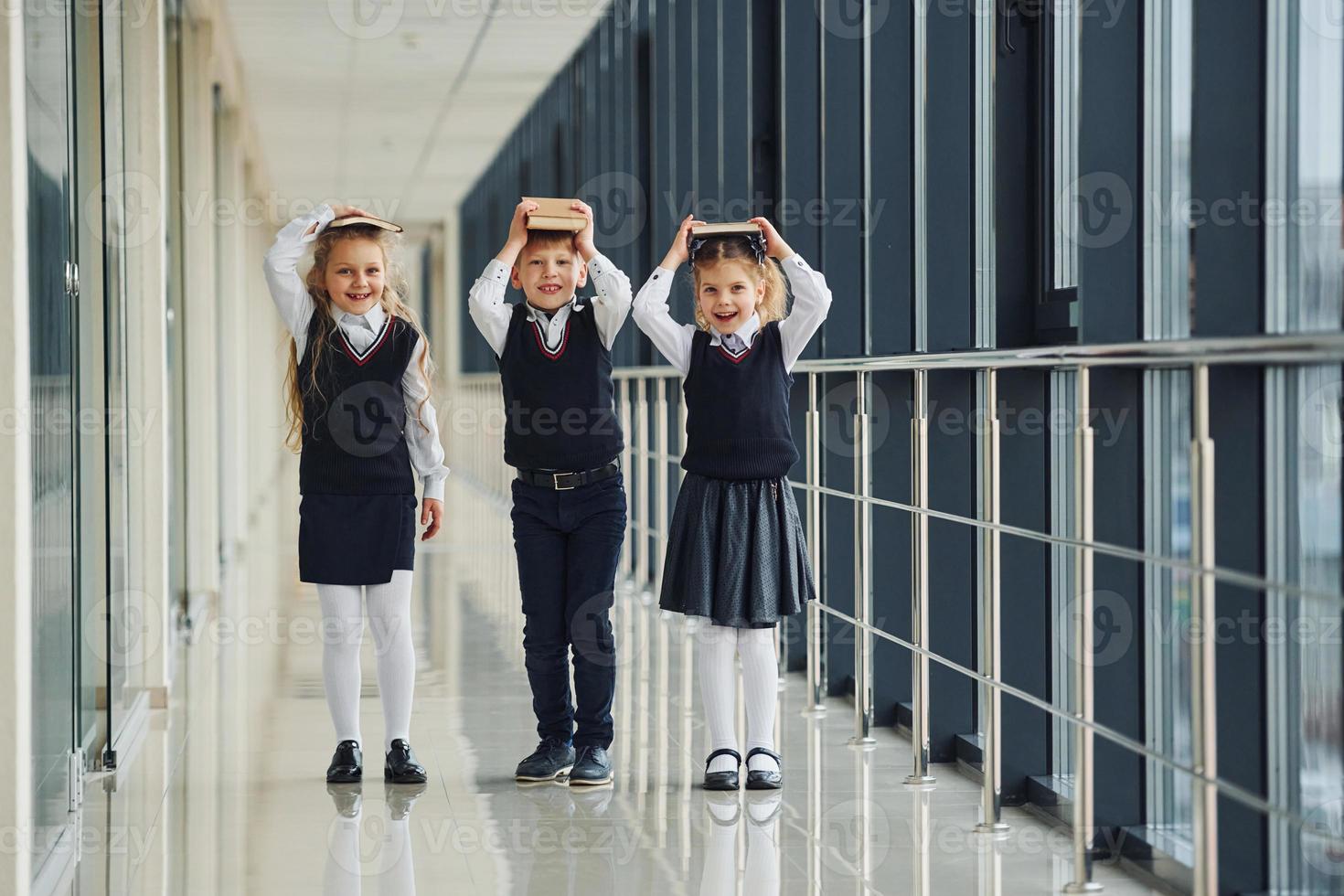 School kids in uniform together with books in corridor. Conception of education photo